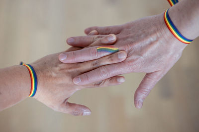 Hands of two women joined together with rainbow bracelets on their wrists