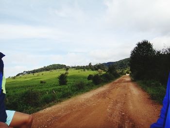 Road amidst trees on field against sky