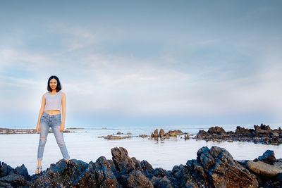 Portrait of young woman standing on rock at beach