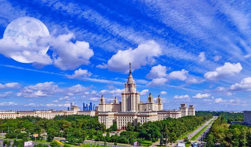 Nice blue cloudy sky with full moon over summer campus of moscow university