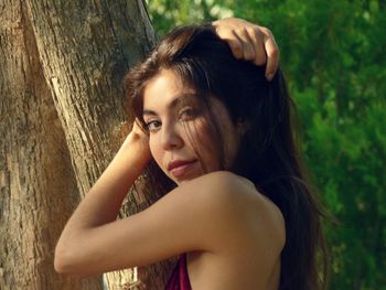 Close-up of young woman with tree trunk