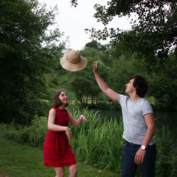 Friends playing with sun hat while standing at park