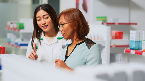 Portrait of smiling young female friends using mobile phone in laboratory