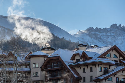 Houses and snowcapped mountains against sky