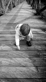 High angle view of girl lying on boardwalk