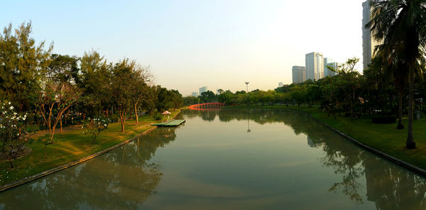 Reflection of trees in lake against sky in city