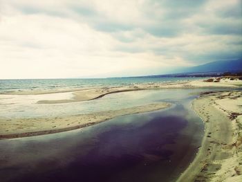 Scenic view of beach against cloudy sky