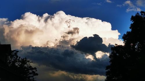 Low angle view of sunlight streaming through clouds