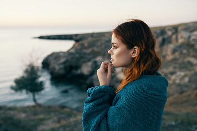 Young woman standing on rock by sea