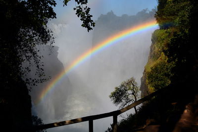 Low angle view of rainbow against mountains in foggy weather