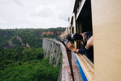 Cropped image of person photographing mountains from train