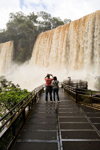 Rear view of man standing against waterfall