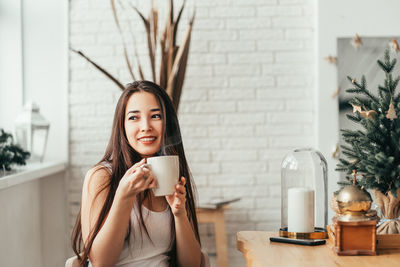 Portrait of young woman drinking coffee at home