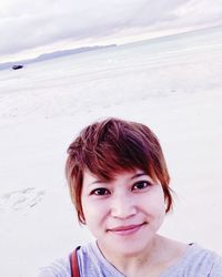 Portrait of woman at beach against cloudy sky