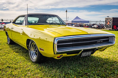 Yellow vintage car on grass in city