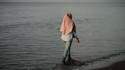 Rear view of woman standing at beach