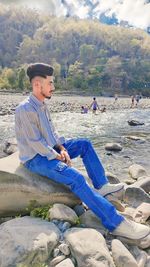 Portrait of young man sitting on rock