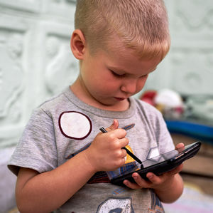 Close-up of boy using phone at home