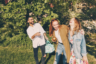 Cheerful young multi-ethnic friends enjoying picnic at back yard during summer