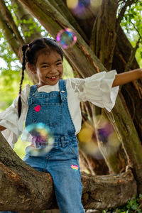 Portrait of smiling girl on tree trunk
