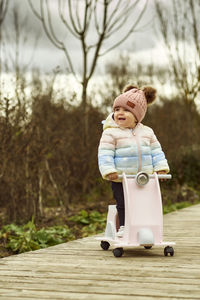 A 1 year old baby girl is with a pink motorcycle outside