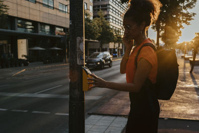 Side view of businesswoman pressing button on footpath while crossing street in city