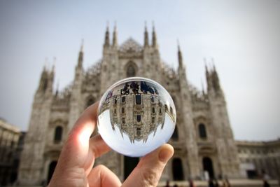 Cropped hand holding crystal ball against milan cathedral 