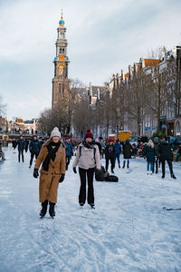 People on snow covered buildings in city