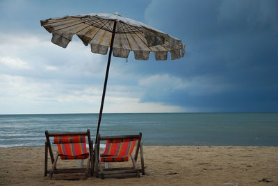 Chairs on beach against sky