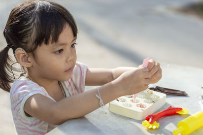 Close-up of cute girl playing with childs play clay at table outdoors