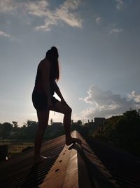 Side view of woman standing against sky during sunset