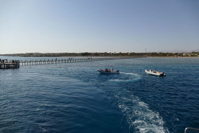 People kayaking in sea against clear sky