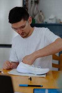 A young man repairs shoes at home.