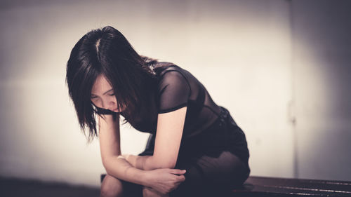 Midsection of woman wearing hat sitting against wall