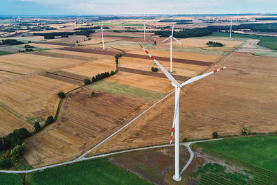 Windmill among agricultural fields. wind turbine generator at summer day