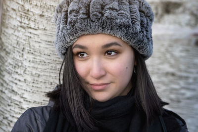 Close-up of young woman wearing knit hat looking away
