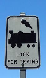 Low angle view of road sign against clear blue sky