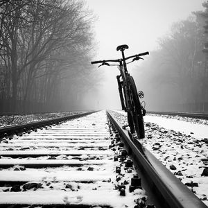 Snow covered railroad tracks by trees during winter