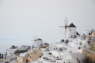 Traditional windmill by buildings against clear sky