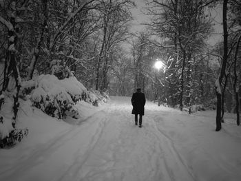 Rear view of man walking on snow covered road