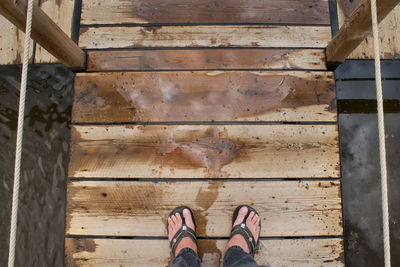 Low section of person standing on pier over lake