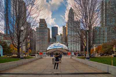 Full length of man with umbrella against sky in city