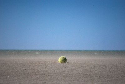 Close-up of ball on beach against clear blue sky