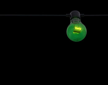 Close-up of illuminated light bulb against black background