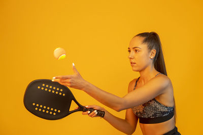 Side view of young woman holding illuminated string lights