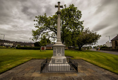 Cross sculpture in park against sky