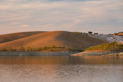 Desert like hill landscape with reflection on the water on a dam lake reservoir  in terena, portugal