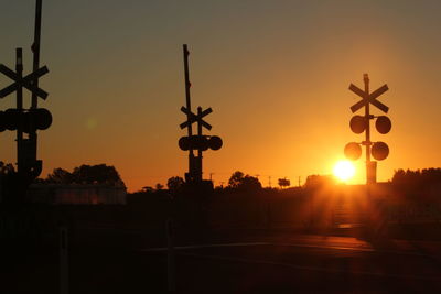 Railroad crossing against sky at sunset