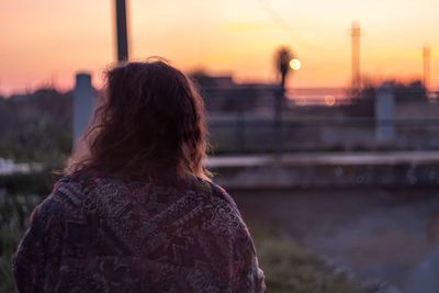 Rear view of man standing on field at sunset