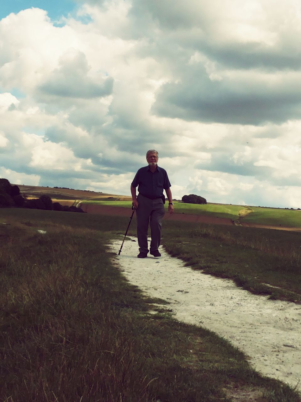 sky, rear view, full length, cloud - sky, landscape, lifestyles, field, leisure activity, grass, tranquil scene, cloud, cloudy, tranquility, walking, casual clothing, men, nature, dirt road